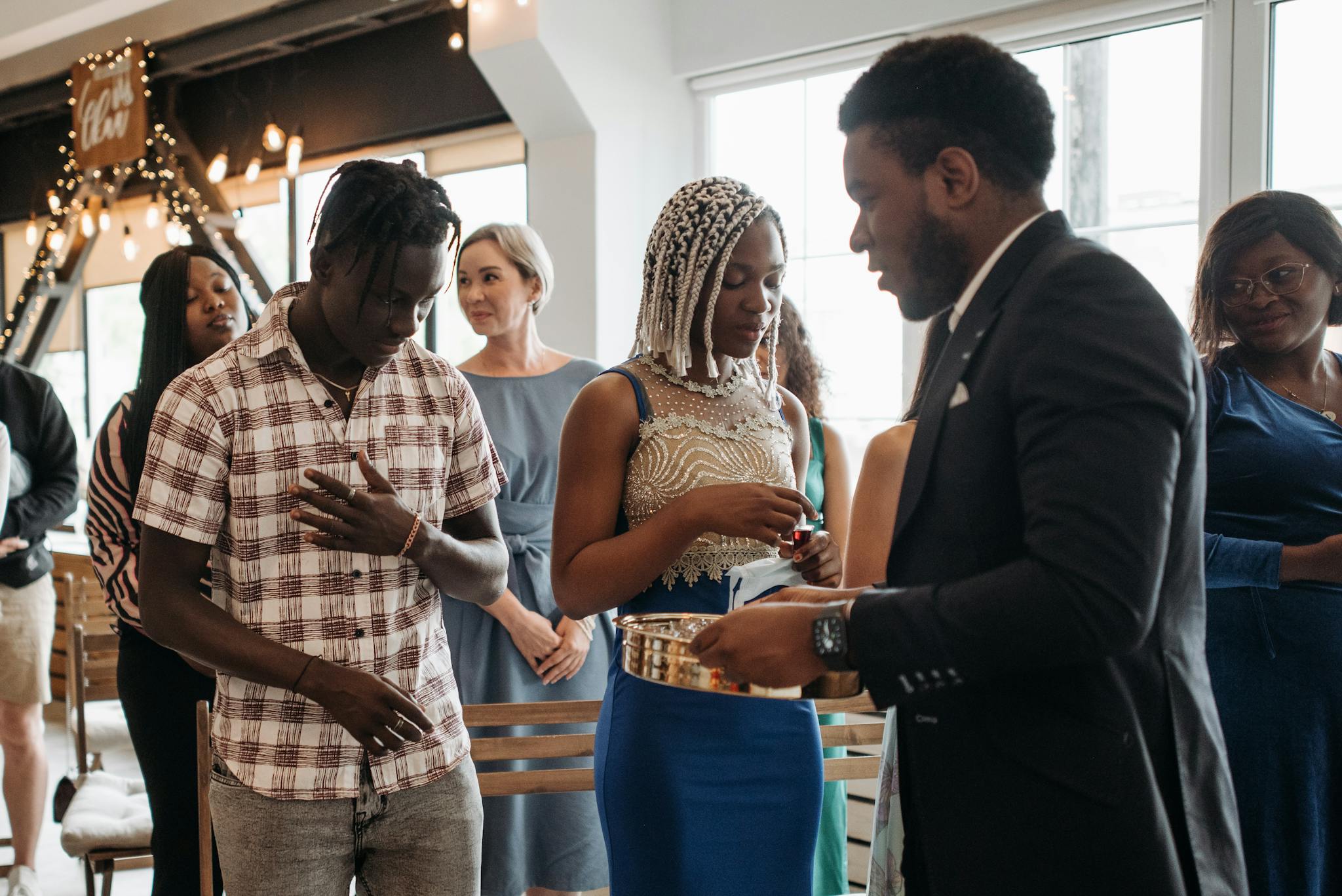 A diverse group of adults partakes in a communion ceremony inside a church.