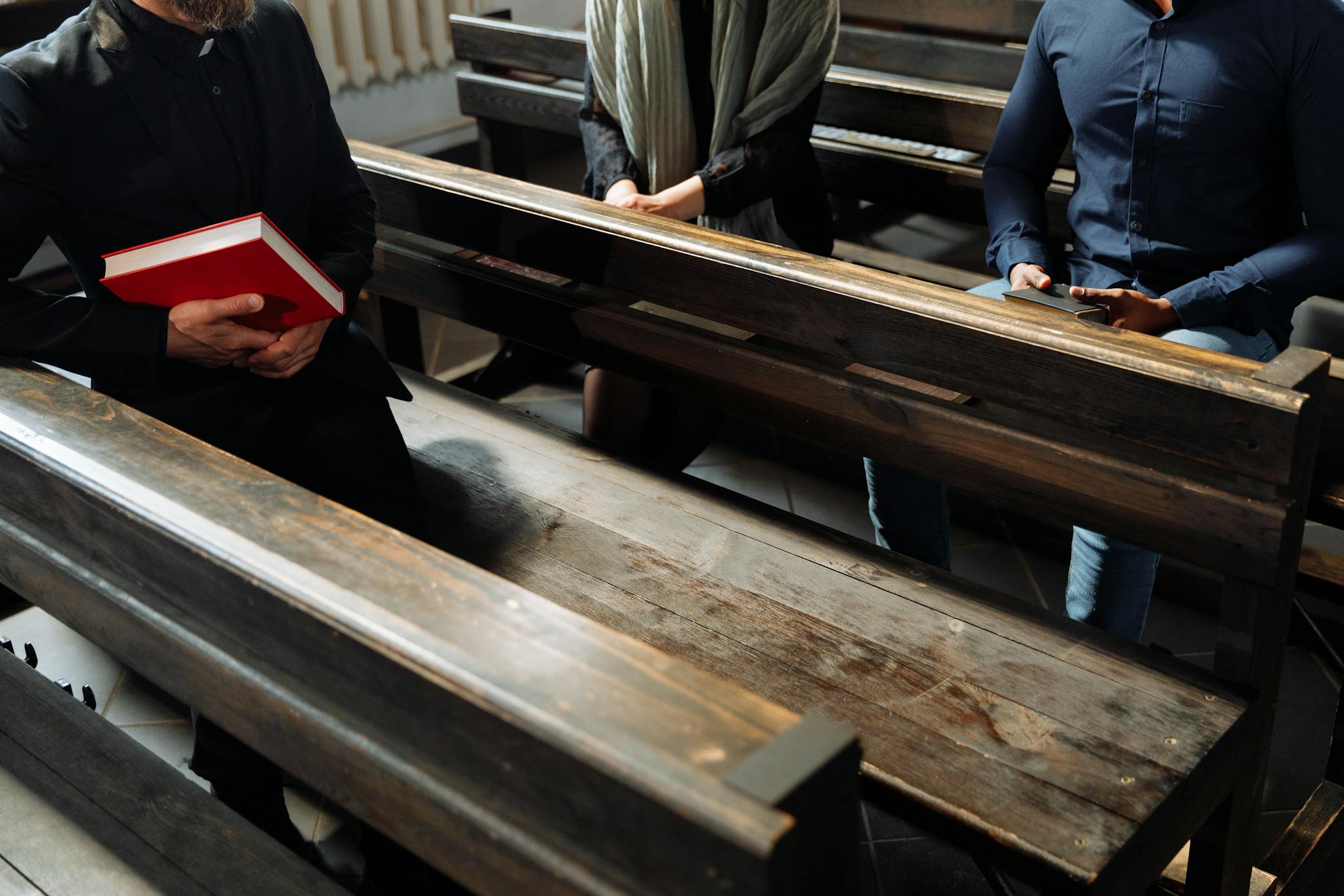 People sitting on wooden benches inside a church with a focus on religious gatherings.